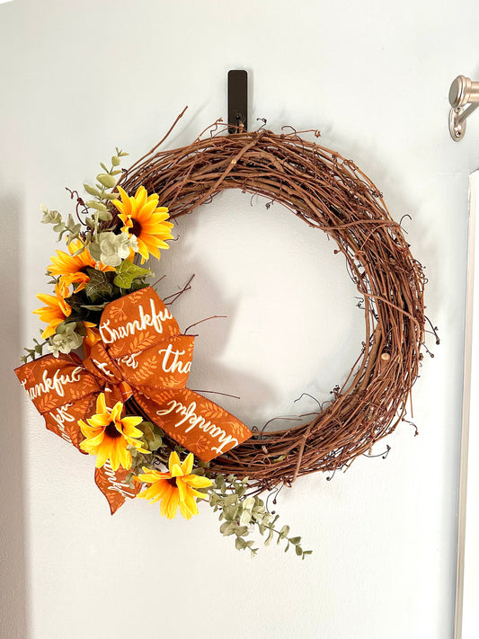 Wreath with sunflowers and 'Thankful' ribbon on a white door