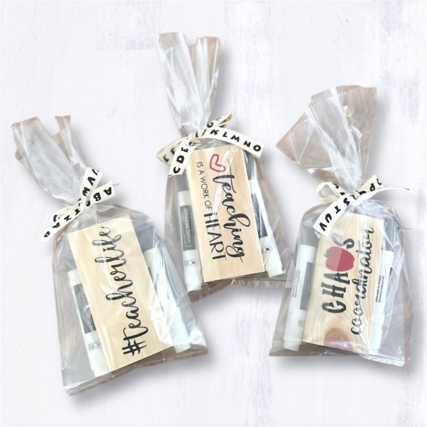 Packaged 'Chaos Coordinator,' 'Teaching is a Work of Heart,' and '#teacherlife,' style teacher eraser kits placed on a cork trivet on a wooden surface
