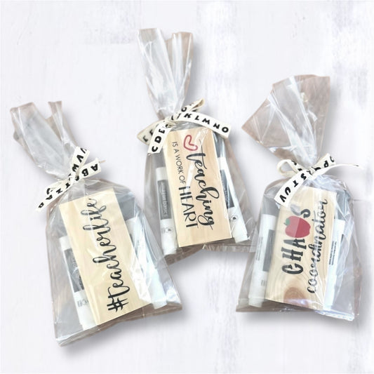 Packaged 'Chaos Coordinator,' 'Teaching is a Work of Heart,' and '#teacherlife,' style teacher eraser kits placed on a cork trivet on a wooden surface