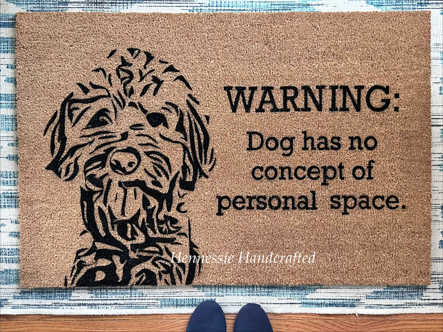 Doormat with a dog illustration and humorous text on a textured floor.