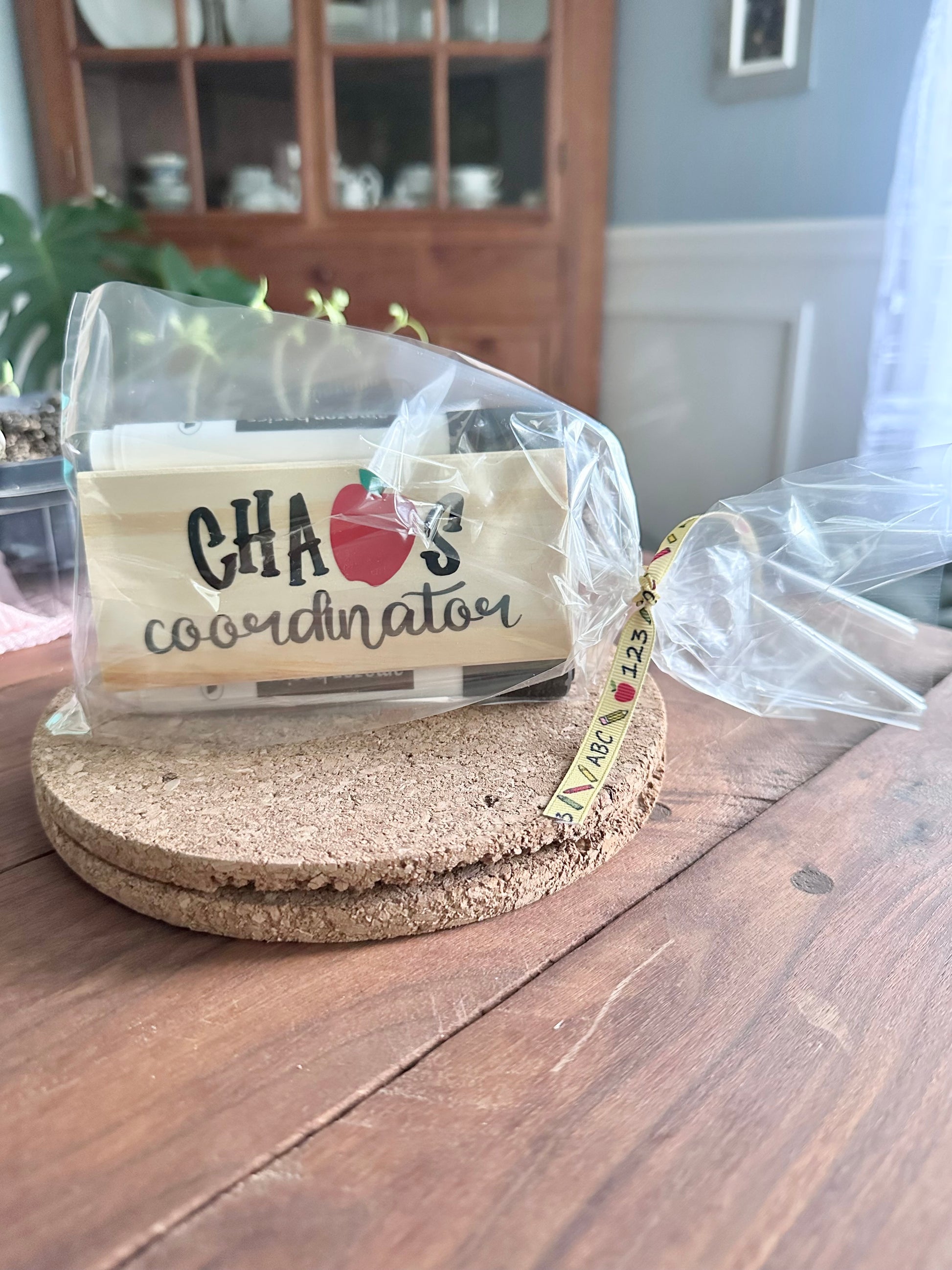 Packaged 'Chaos Coordinator' style teacher eraser kit placed on a cork trivet on a wooden surface